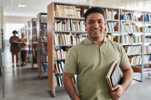 Portrait of adult student smiling at camera while standing in the library