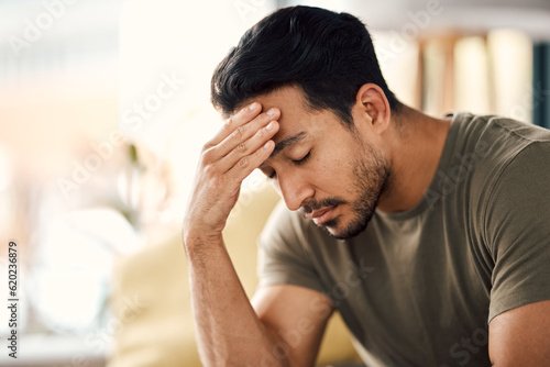 Tired, headache and stress of man in living room with mental health, fatigue and sad problem. Face, depression and frustrated male person with anxiety, brain fog or crisis of failure, mistake or debt
