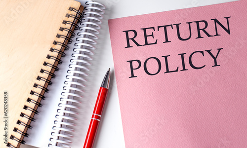 RETURN POLICY word on the pink paper with office tools on white background