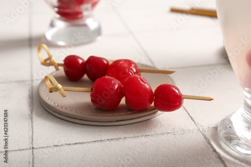 Tasty maraschino cherries on white tile background