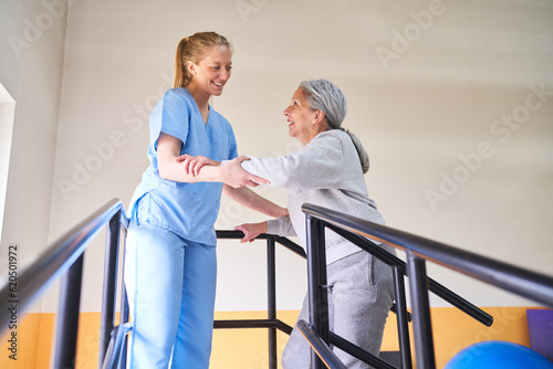 Young physiotherapist assisting elderly woman in movement therapy