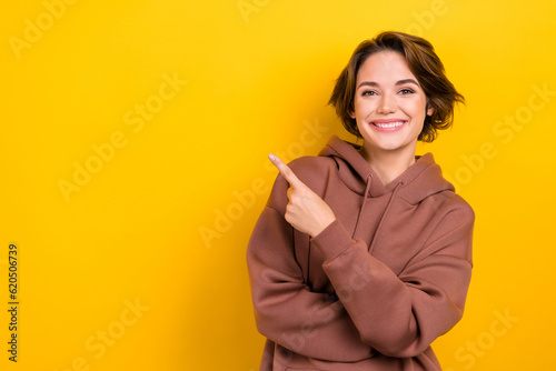 Photo of adorable lady indicate finger empty space offer shopping center mall wear brown hood shirt isolated yellow color background