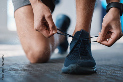 Fitness, shoes and tie with a sports man in the gym getting ready for a cardio or endurance workout. Exercise, running and preparation with laces of a male athlete or runner at the start of training