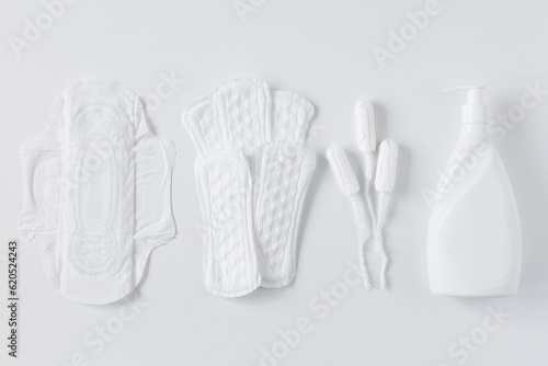 Tampons, feminine cotton sanitary pads and liquid intimate soap on a white background