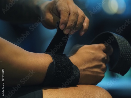 Close up hands men holding and putting arm wrap bandages weight kilograms, arm dumbbell, fitness, gym, training, power, sport, health, exercise 