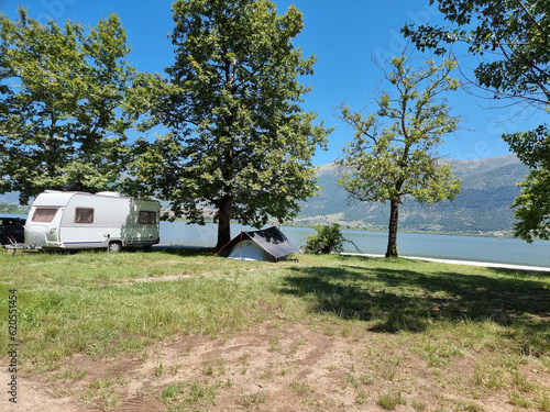 caravan car and trailer tent by the lake and green platanus trees in summer holidays