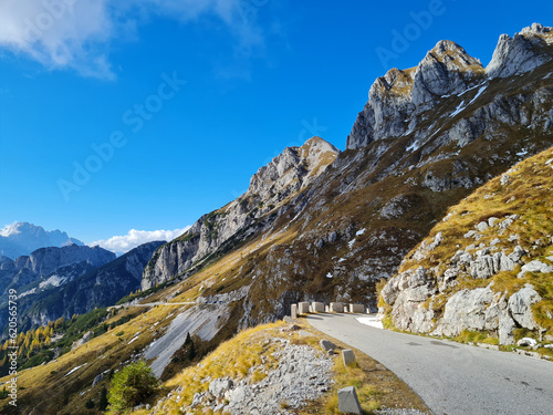 Alpine road over meadows under rocky peaks