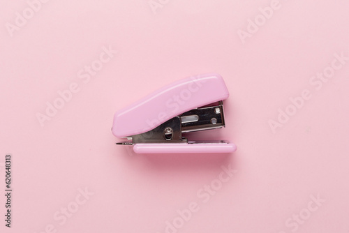 Pink stapler on color backgroung, top view