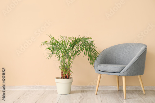 Armchair and houseplant near beige wall