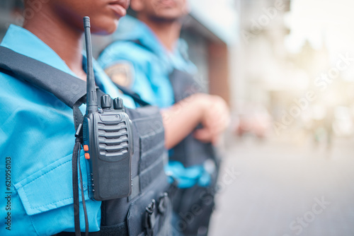 Radio, police and surveillance with a black woman officer standing outside while on patrol in the city. Walkie talkie, dispatch or communication with a female security guard in an urban town