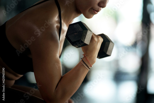 Fitness girl lifting dumbbell weights at the gym, doing exercises with dumbbell, fitness muscular body