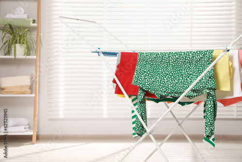 Different apparel drying on clothes airer in room, space for text