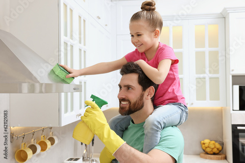 Spring cleaning. Father and daughter tidying up in kitchen together