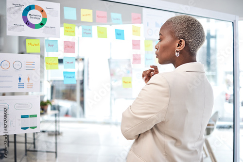 Black woman, thinking and glass board for project management, marketing or planning at office. African female person, manager or employee checking project plan, tasks or statistics at the workplace