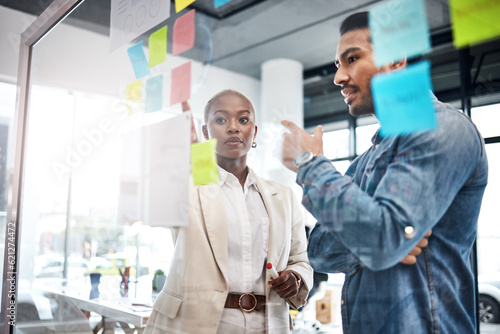 Creative people, thinking and meeting for schedule planning, brainstorming or team strategy at the office. Man and woman in teamwork decision for project plan, tasks or sticky note ideas in startup