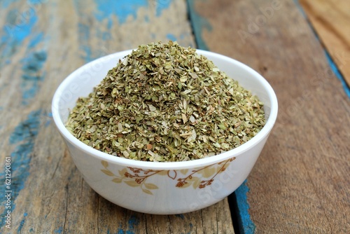 Dried oregano spice in a bowl on wooden background 