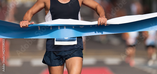 Man running towards the finish line, male runner win the race outdoor in the city. Passes finish line as a winner