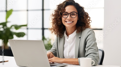 Smiling female professional executive using computer in corporate office looking at camera