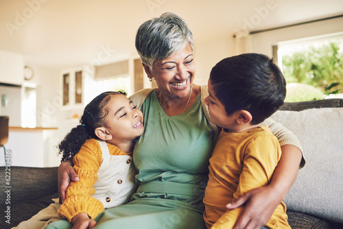 Hug, grandmother or happy kids on a sofa with love enjoying quality bonding time together in family home. Smile, affection or funny senior grandparent with children siblings on house couch laughing