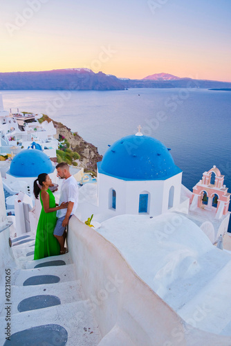 Couple hugging and kissing on a romantic vacation in Santorini Greece, men and women visit the whitewashed Greek village of Oia .