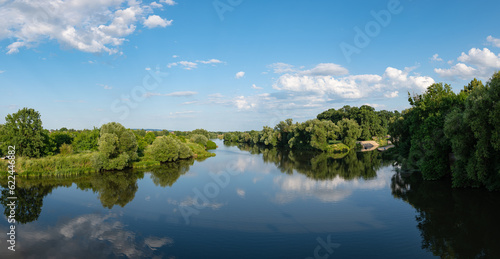 Panorama rzeki Odry w tle lekko pochmurna pogoda, błękit nieba zieleń przy brzegu, pora letnia, Odra w odcinku województwa Opolskiego 