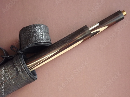 Two-piece billiard cue in a brown leather case on an brown background. High quality photo