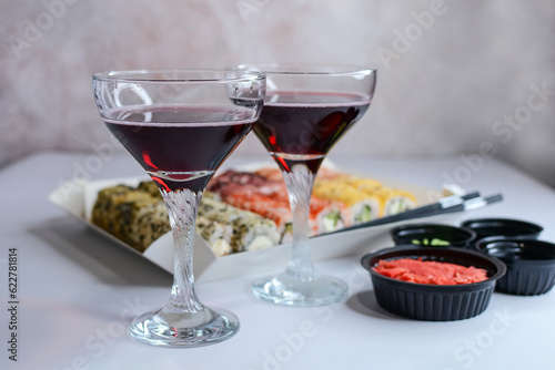 Holiday concept. Glasses with red wine, sushi and spices for sushi on the table on an abstract background