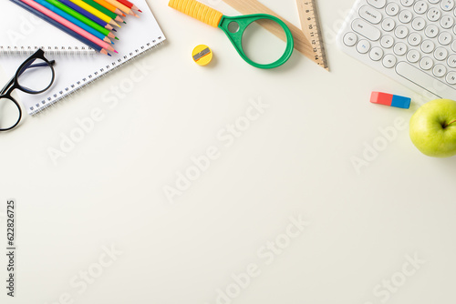 Embrace the flexibility of online studying from home with this top-view photo featuring a keyboard, notepads, colorful pencils and glasses on white background. Empty space for text or ads