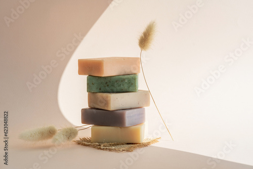 Pattern natural handmade soap of different sizes and colors. Brown background shadows of flowers from the sun. Cosmetic pedestal for product promotion.