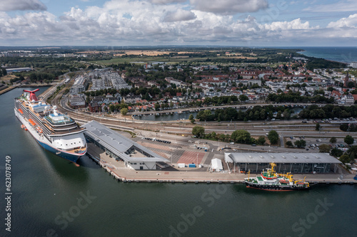 Rostock, Warnemuende, Germany, The cruise ship "Carnival Pride" of Carnival Cruise Line has moored at Cruise Ship Terminal, in Warnemuende with its landmarks in the background - aerial view 