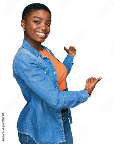 Young african american woman wearing casual clothes inviting to enter smiling natural with open hand