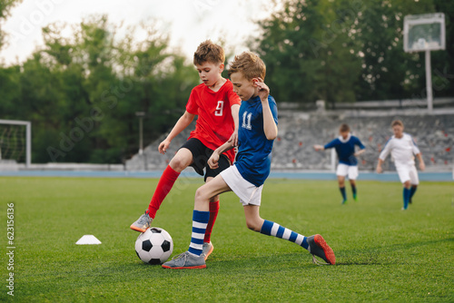 Boys playing football game on a school tournament. Football soccer match for children. Dynamic, action picture of kids competition during playing football