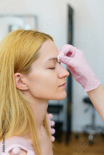 Close-up of a young woman's face during eyebrow correction in the salon