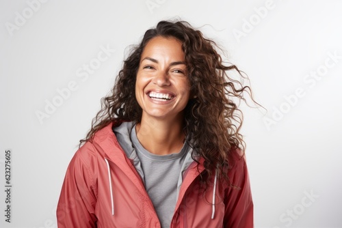 Lifestyle portrait photography of a pleased Brazilian woman in her 40s wearing a lightweight windbreaker against a white background 