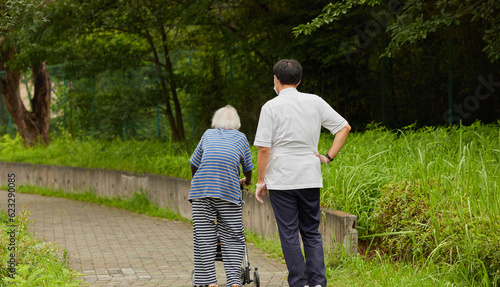 真夏の公園で散歩している障害者のシニア女性と看護師の姿