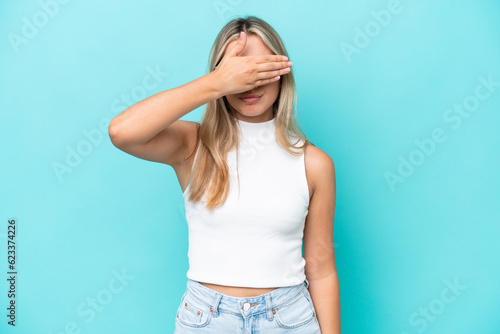Young caucasian woman isolated on blue background covering eyes by hands. Do not want to see something