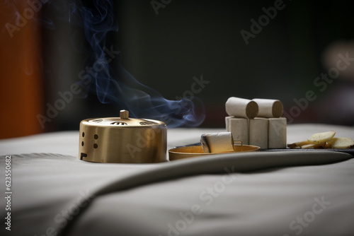 Moxibustion treatment - traditional Chinese medicine tools for acupuncture points heating therapy. Chinese herbal medicine. Moxibustion copper burner box with moxa herbal sticks in holistic spa.