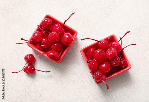 Bowls of tasty maraschino cherries on light background