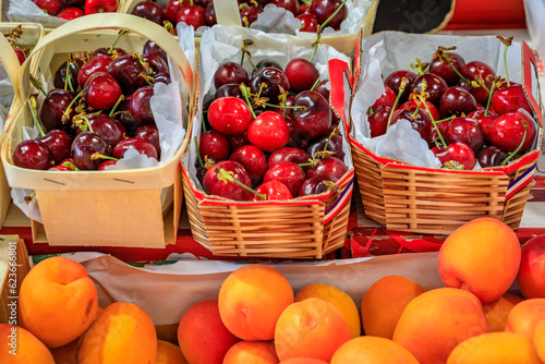Ripe red cherries and apricots at a farmers market at a local covered provencal farmers market hall in the old town or Vieil Antibes, South of France