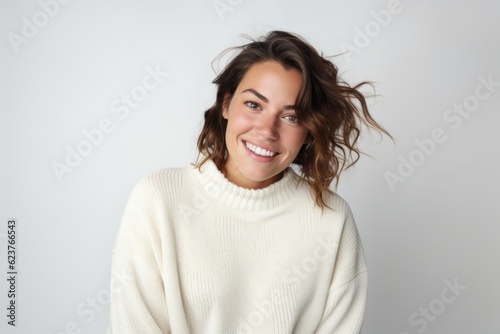 Portrait of a smiling young woman in white sweater on white background