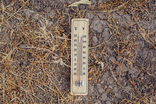 Hot weather. Thermometer in hand in front of an urban scene during heatwave. High temperature concept