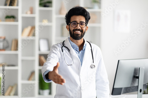 Friendly handsome middle eastern doctor outstretching hand and smiling