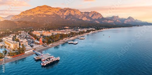 Discover the perfect blend of coastal beauty and mountainous charm with striking aerial photo, showcasing Kemer's hotels overlooking a scenic beach and breathtaking mountains