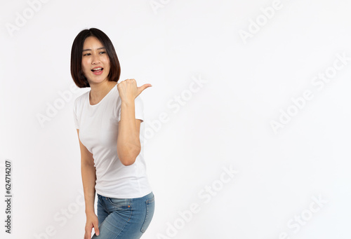 portrait of a Happy Asian woman smiling points her index finger at an empty space in the background and looks straight ahead on white background