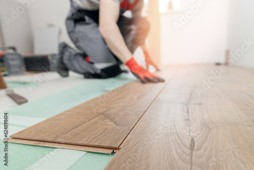 Professional worker Installing laminated or wood parquet on floor, man holding wooden tile