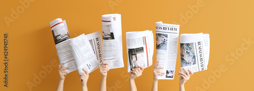 Female hands with newspapers on orange background