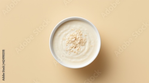 Top view of bowl of oatmeal on yellow background, minimal design.