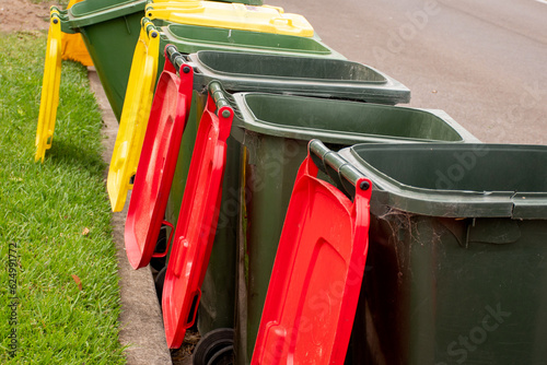 Australian garbage wheelie bins with colourful lids for general and recycling household waste on the street kerbside for council rubbish collection.