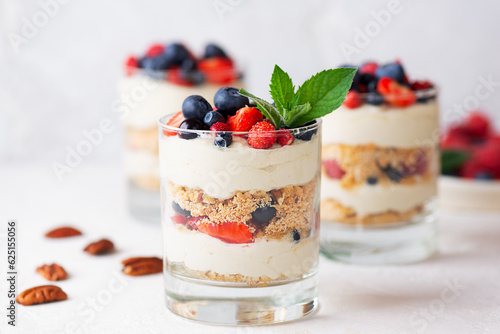 Vegan dessert in a glasses with berries, mint, nuts, whipped cream and biscuit. Healthy food, sugar, gluten and lactose free.