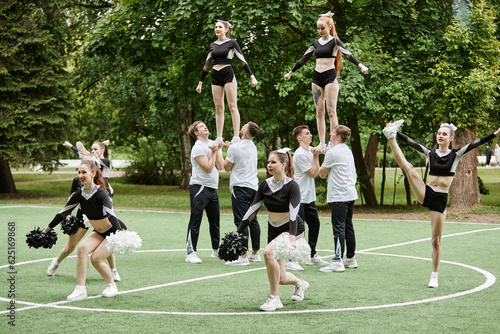 Cheerleader team doing tricks and dancing with pompom at sport competition outdoors